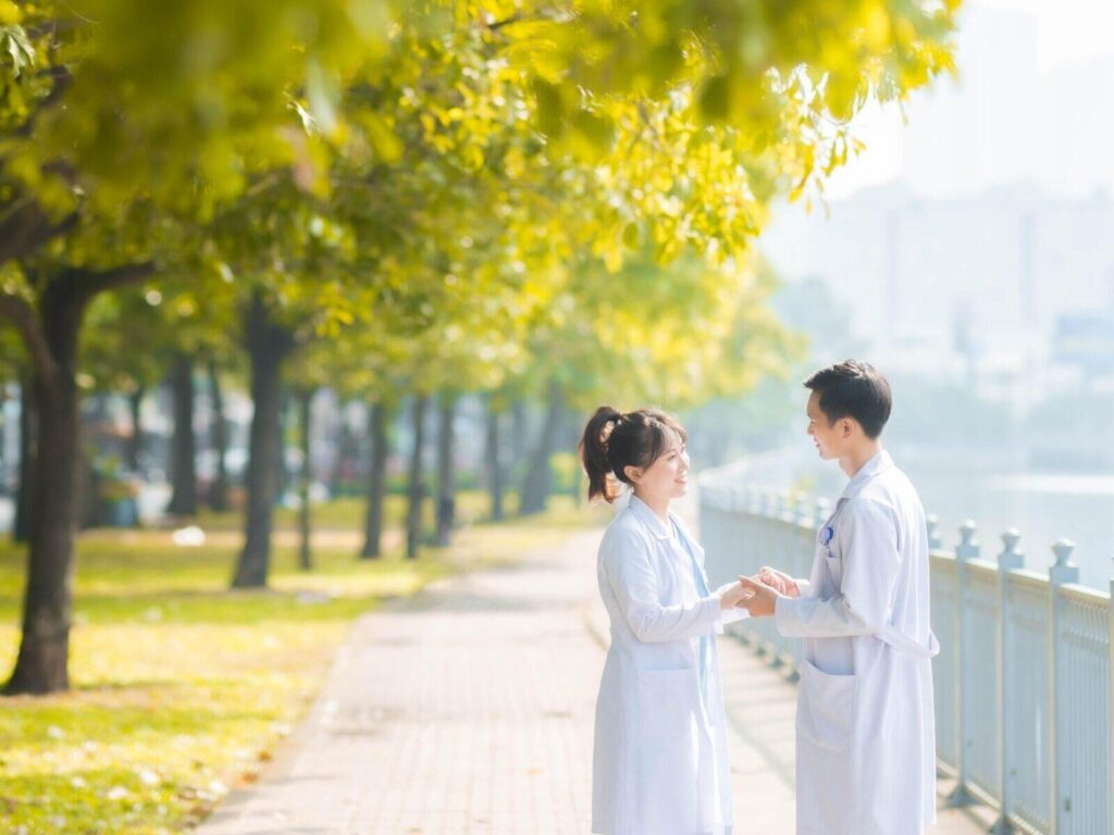 Two doctors talking on a sunny path.